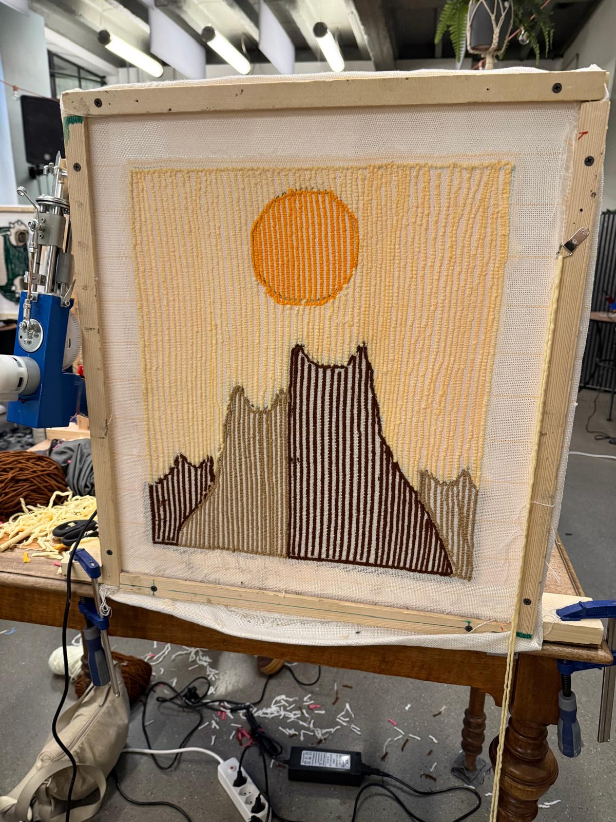 Toile tendue sur son métier avec un paysage de montagne en cours de tuftage